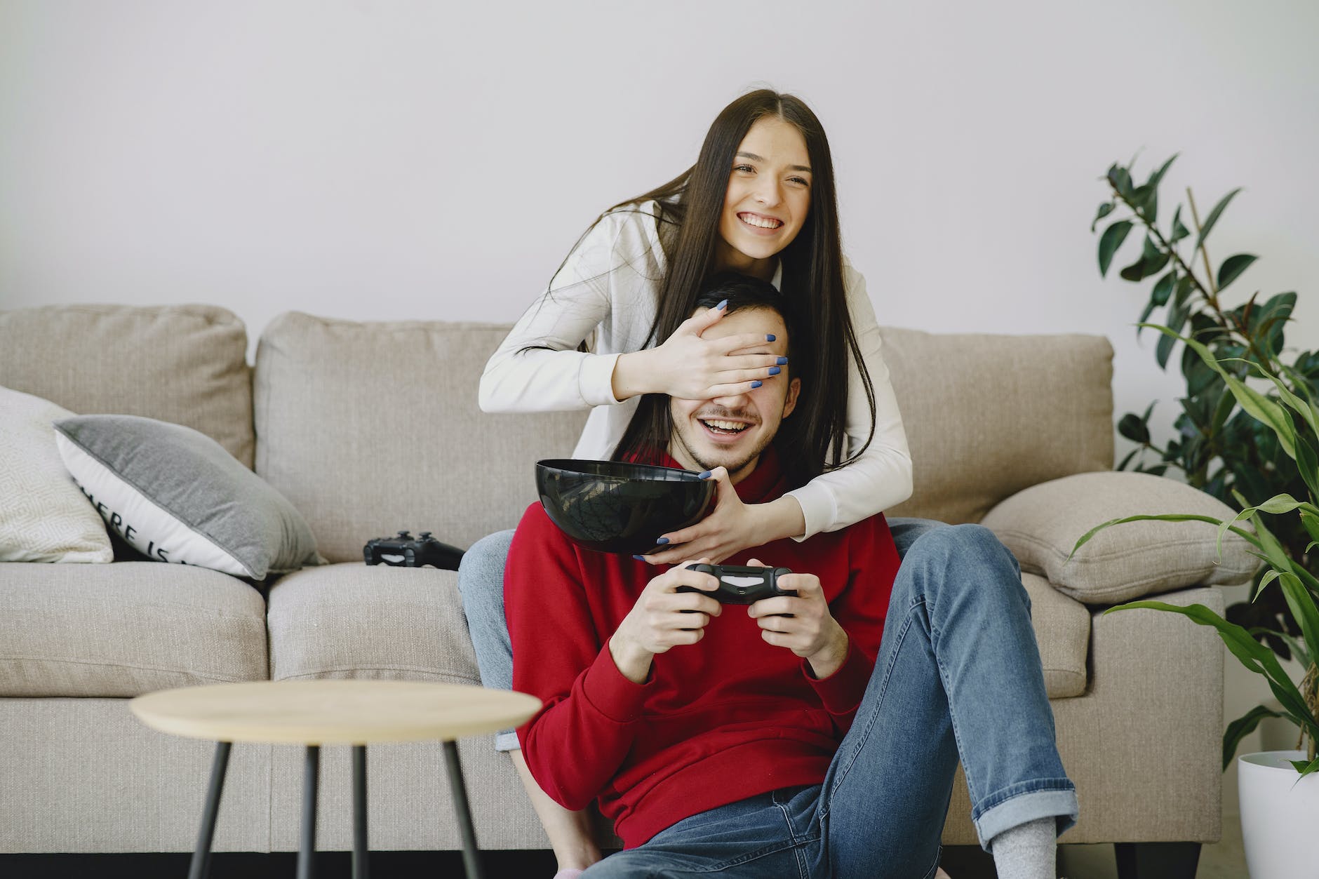 woman covering partners eyes with hand while playing game console