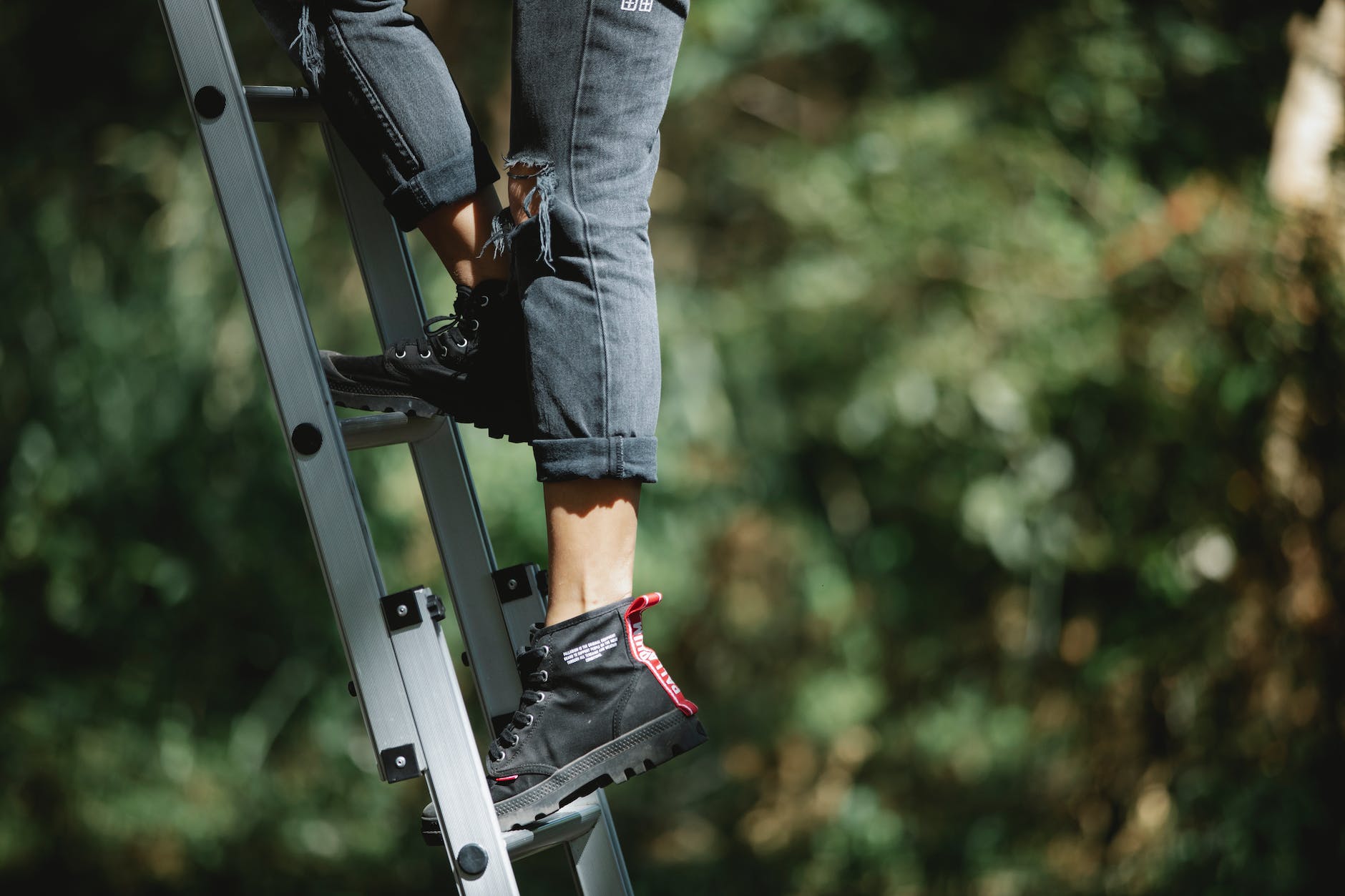 faceless camper climbing ladder in forest