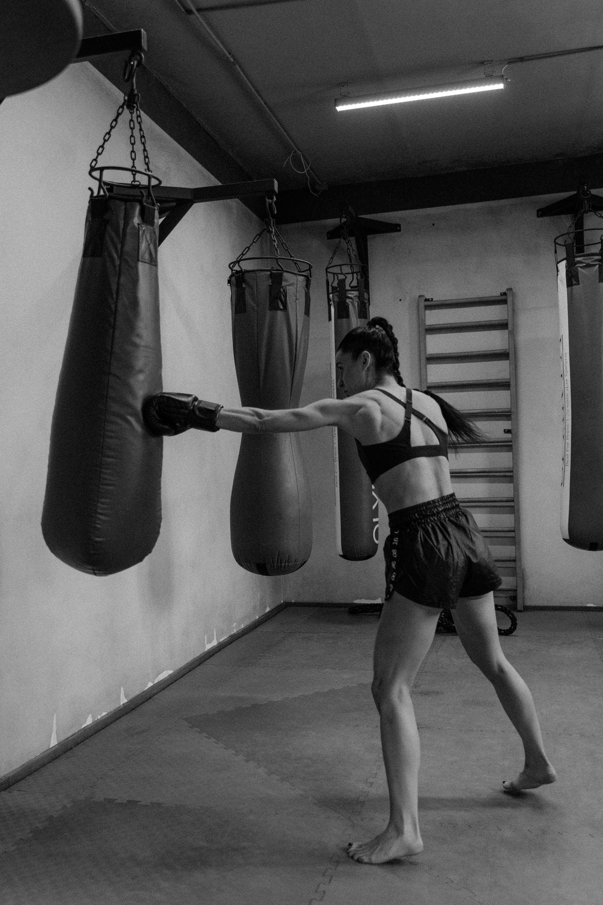 woman practicing self defense strikes on a punching bag in the gym