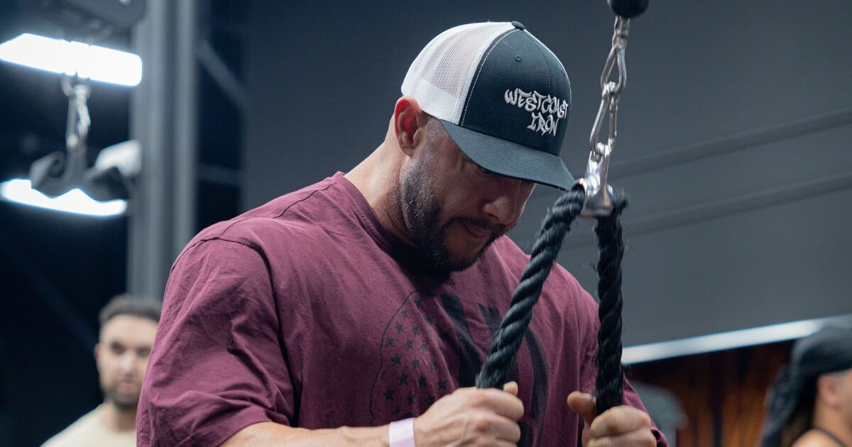 man performing rope cable tricep pushdown in gym